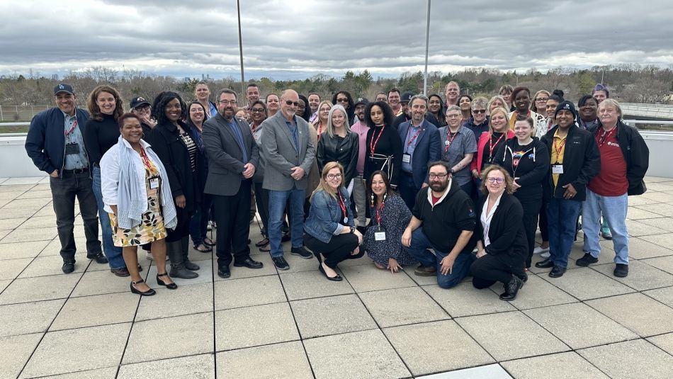 A large group photo outside under gray cloud on a terris