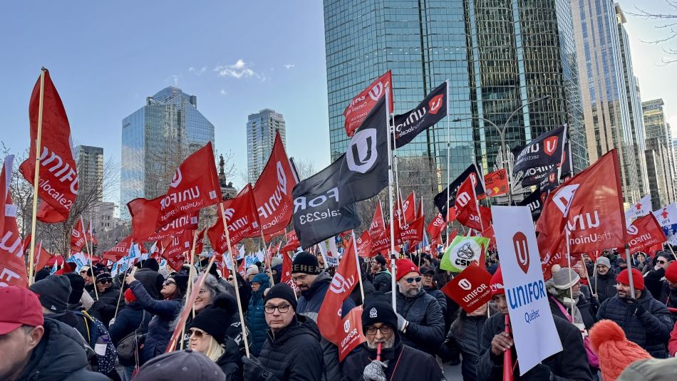 Une foule nombreuse brandissant des drapeaux rouges d'Unifor