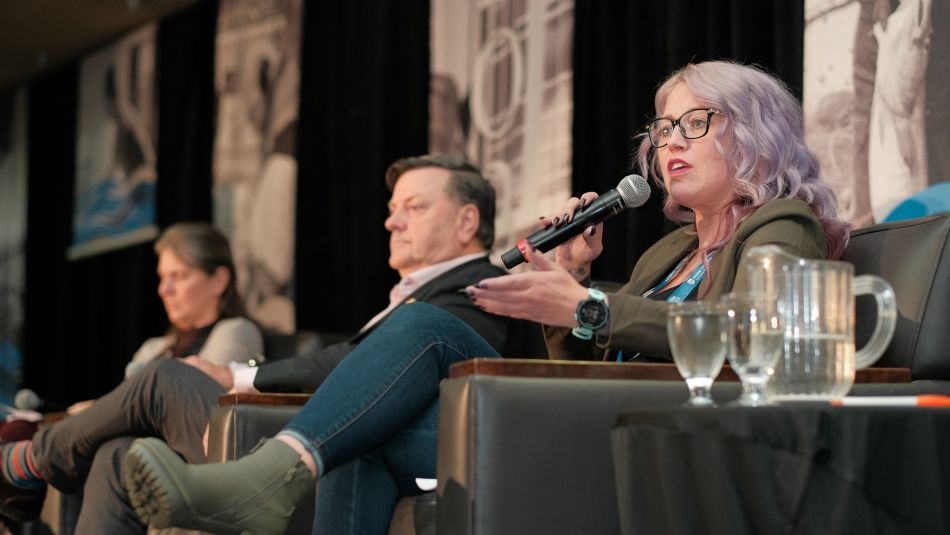 FFAW-Unifor President Dwan Street holds a microphone and speaks on stage in a panel with two others 