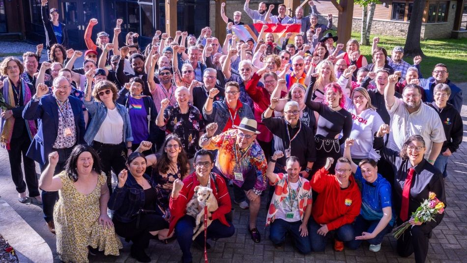 Pride Conference delegates post for a group photo with fists raised in air.