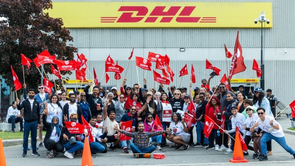 large group of people standing outside DHL plant with Unifor flags