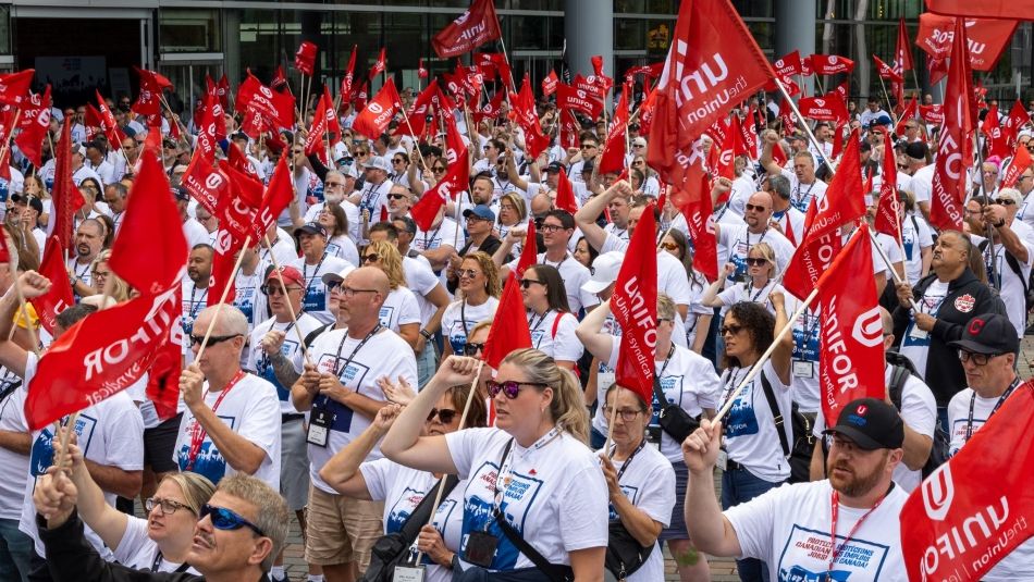 A group of people holding flags and wearing Protect Canadian Jobs! shirts.