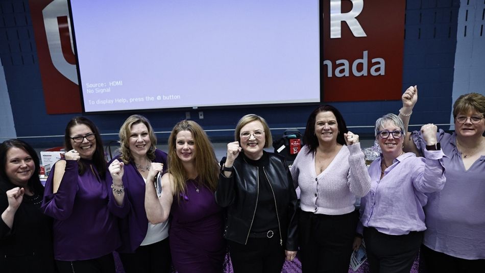 Unifor National President Lana Payne with a group of Unifor sisters, all with fists raised in solidarity.