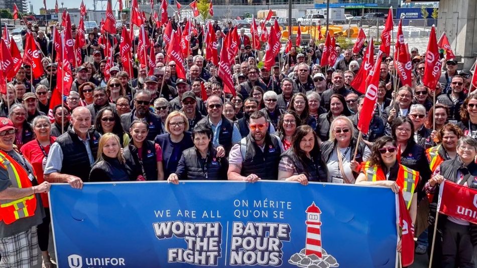 A large crowd at a rally behind a large banner that reads, Worth the Fight!