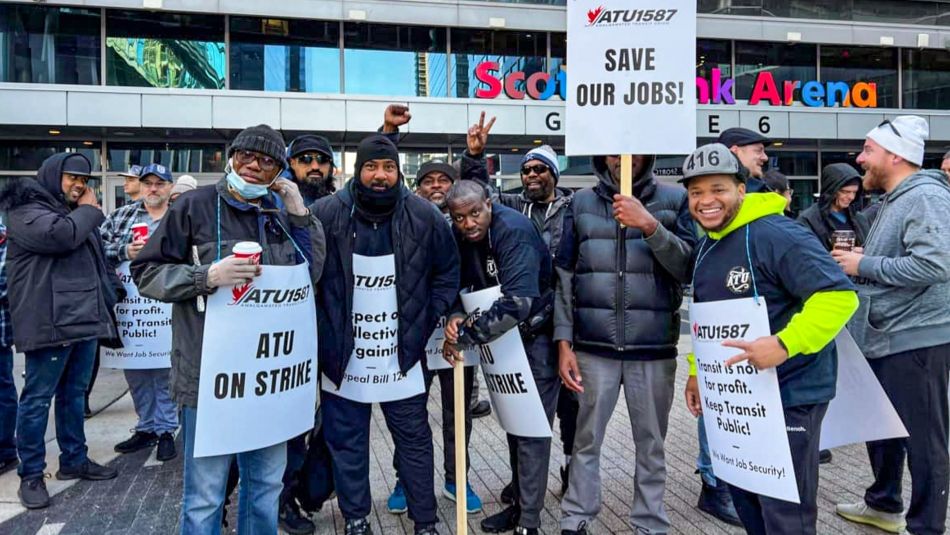 Several members of ATU Local 1587 posing for photo outdoors holding placards reading "Save Our Jobs"