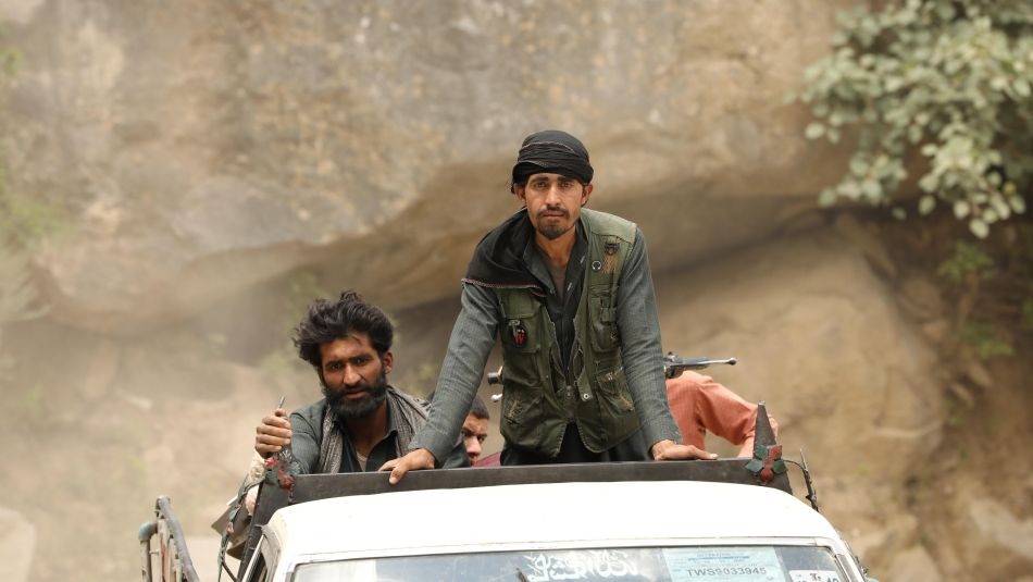 three taliban fighters ride in back of white pickup