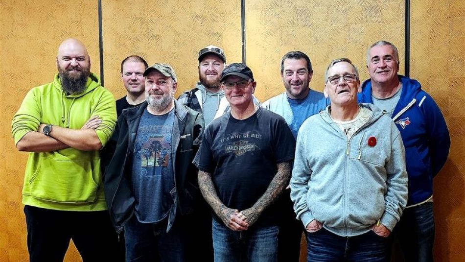eight men standing in front of a panel wall