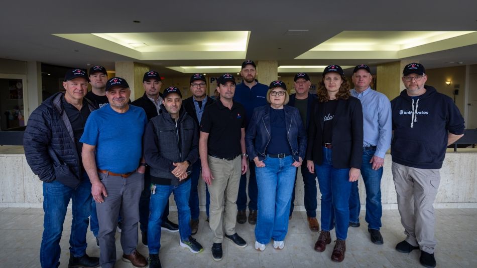 Un grand groupe portant des chapeaux Unifor avec les coudes en l'air