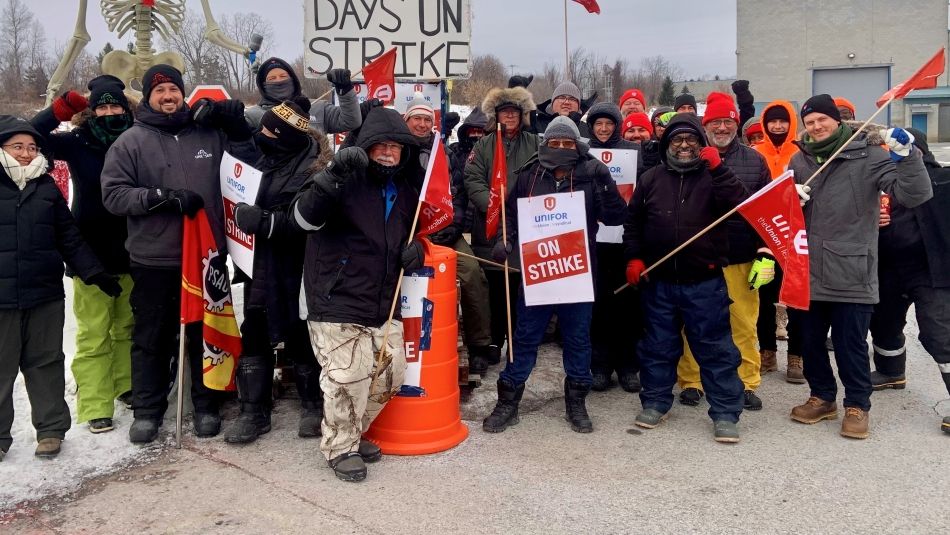 A group of people with strike signs outside in winter.