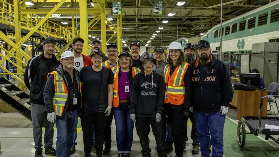 Unifor leaders on a tour of the Alstom plant A group of people posing for a photo inside an industrial facility wearing PPE