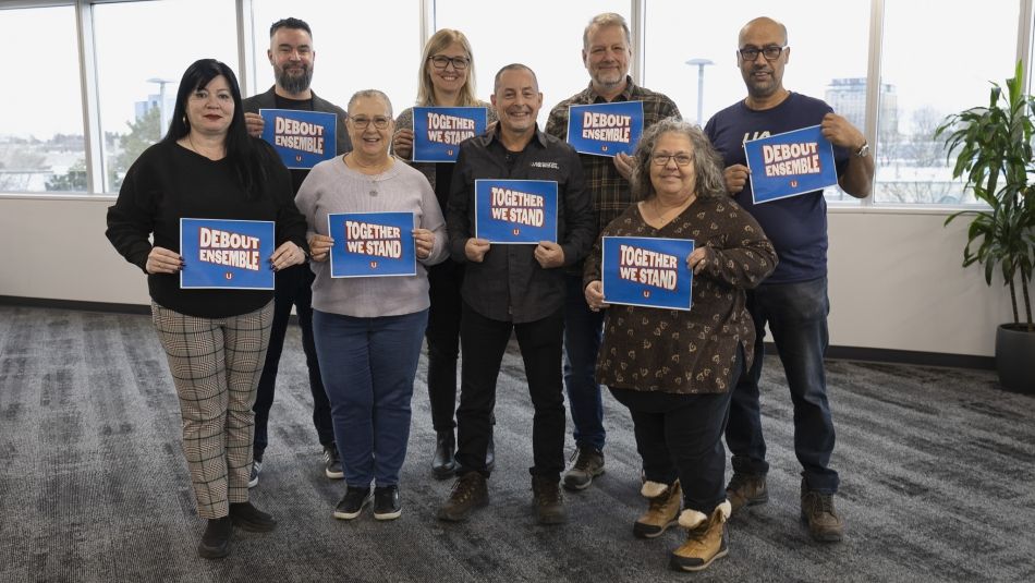 A group of people holding placcards that read; Together we stand with a Unifor logo