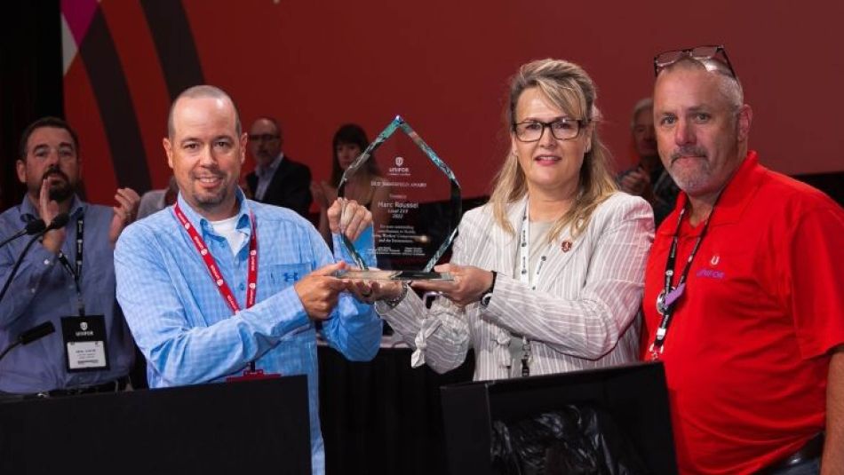 Three people holding up an award