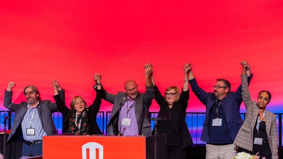Leadership on stage at Canadian Council holding hands raised up