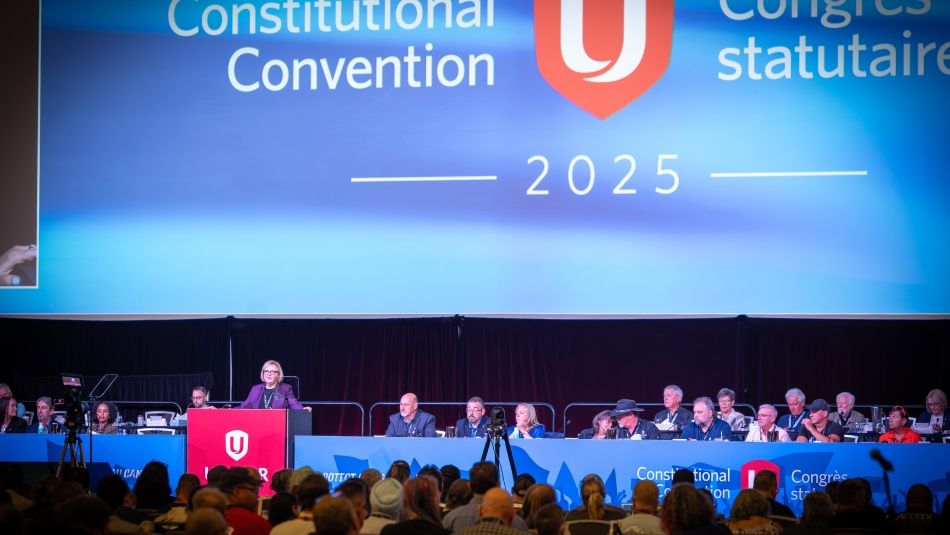 A women at a podium in front of presentation screens