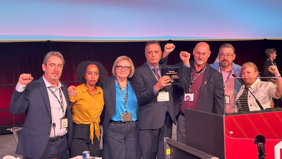 A group of people surrounding a man holding up an award.