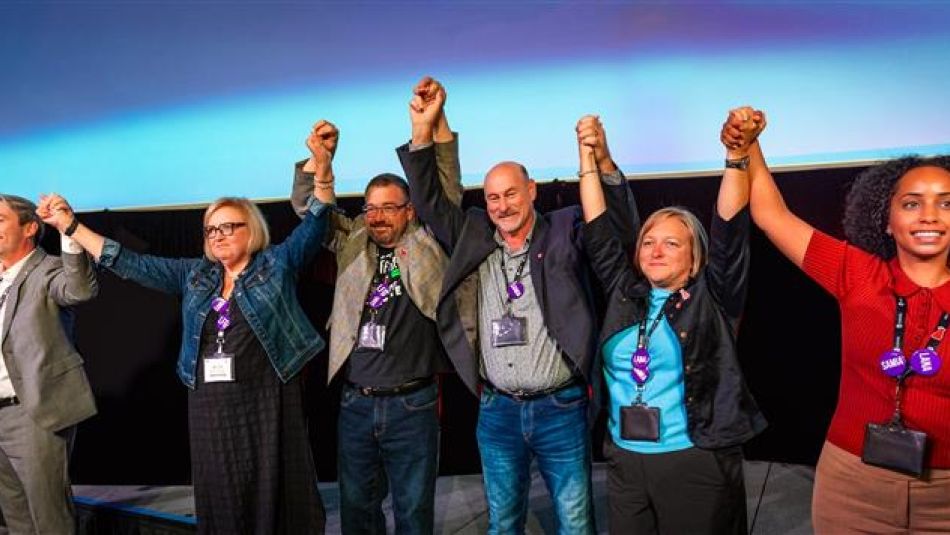 Six people holding hands with their arms raised