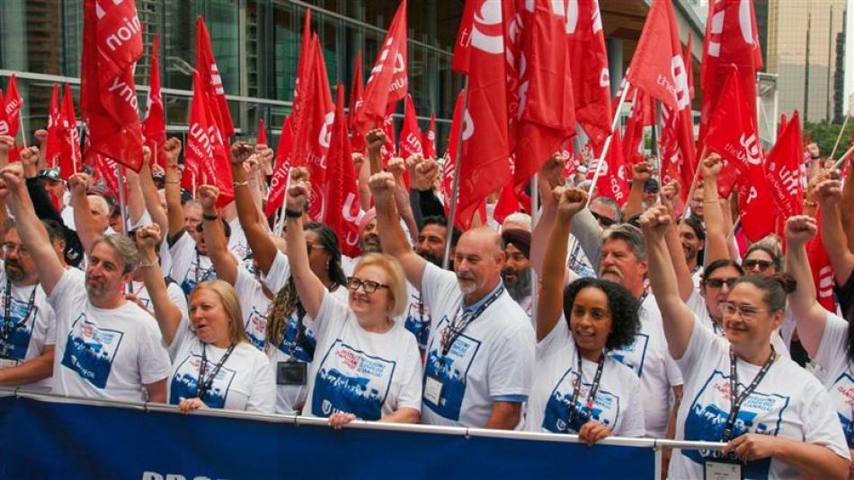 A large crowd wearing white t-shirts and holding red flags
