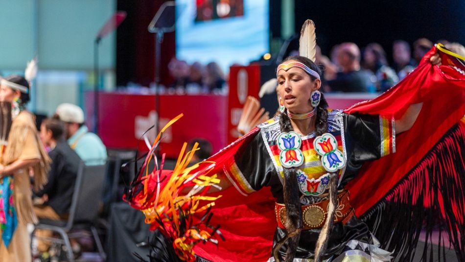Indigenous dancer in front of Canadian Council table.