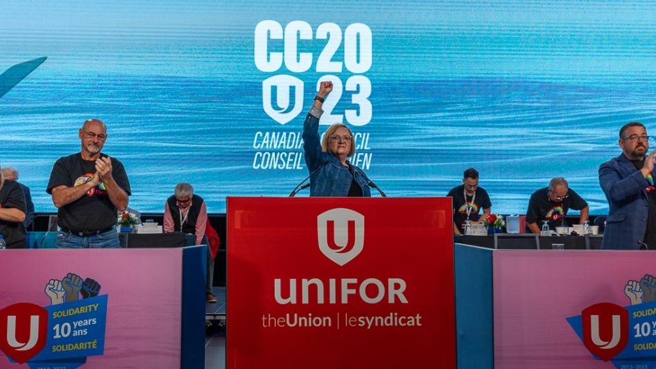 A woman raising her fist in the air as others applaud on a stage.
