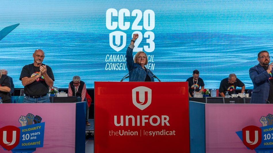 A woman raising her fist in the air as others applaud on a stage.