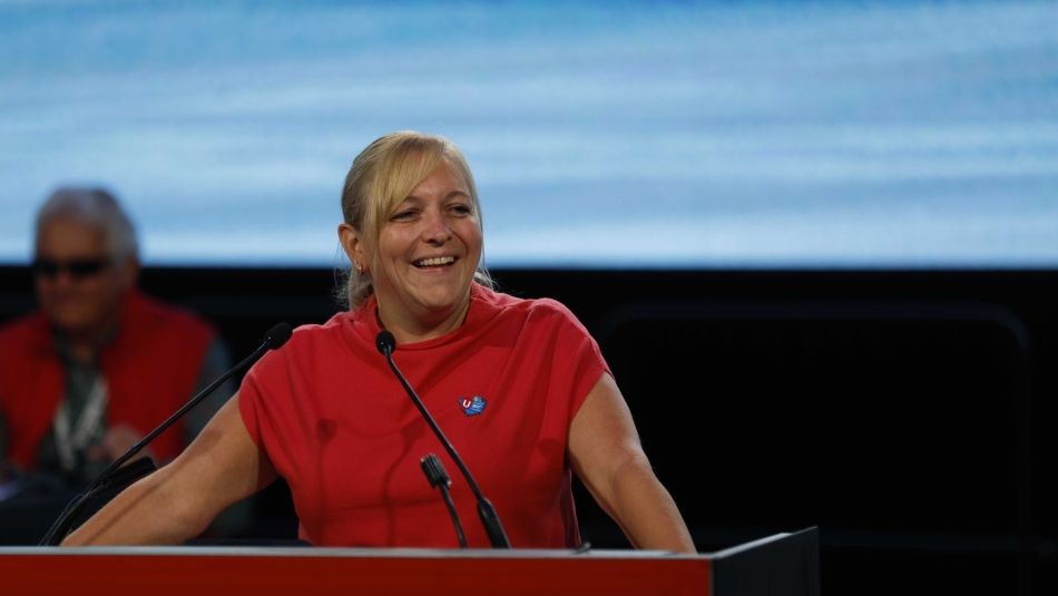 Jennifer Murray wearing a red shirt speaks at the podium.