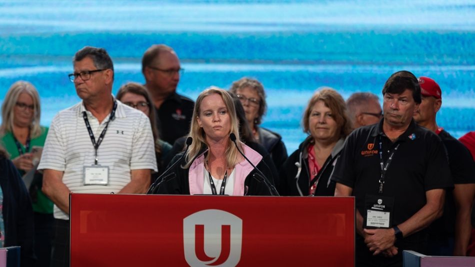 Un groupe de personnes devant un podium rouge d’Unifor.