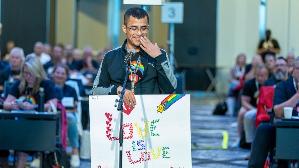 A person at the microphone holds a sign that says, "Love is love."