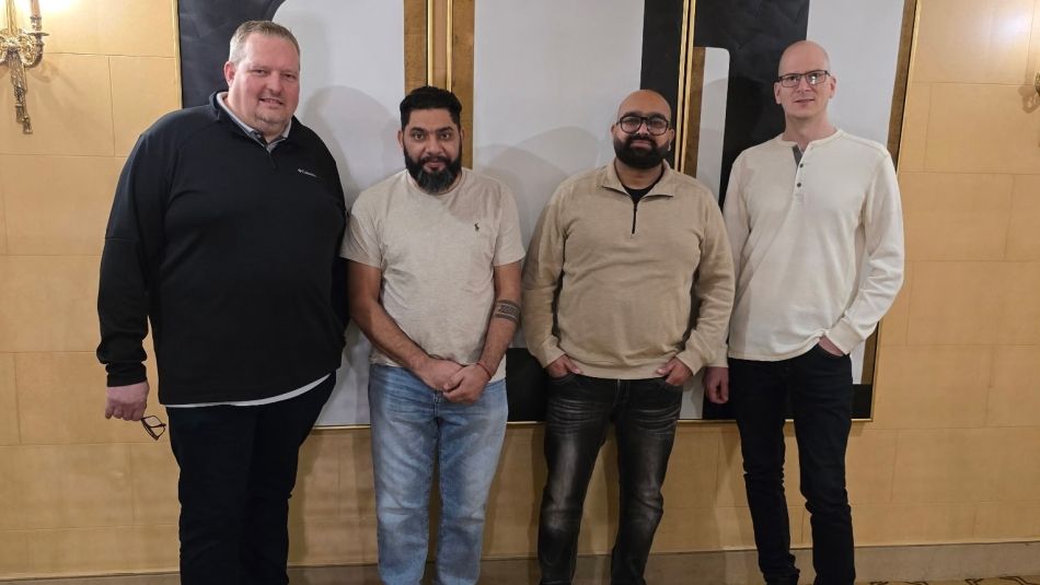 Four men standing in front of a beige wall