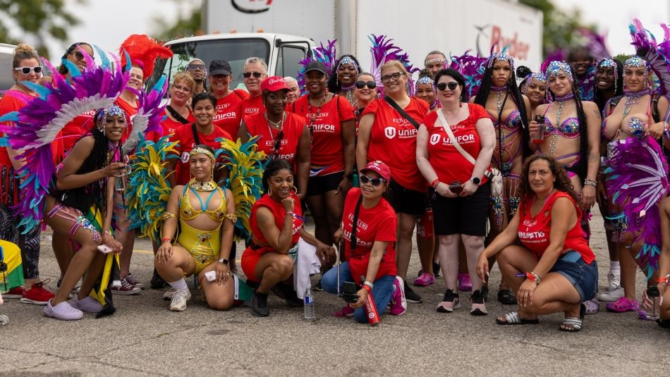 A group of people posing for a photo some dressed in Caribbean traditional regalia