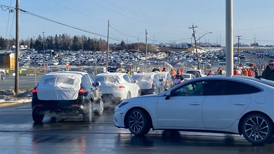 Une file de voitures, conduites par des briseurs de grève, franchit un piquet de grève à l'entrée d'un parking de l'Autoport de CN Rail