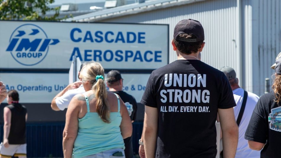 Unifor members walking on the picket line in front of a sign that reads Cascade Aerospace
