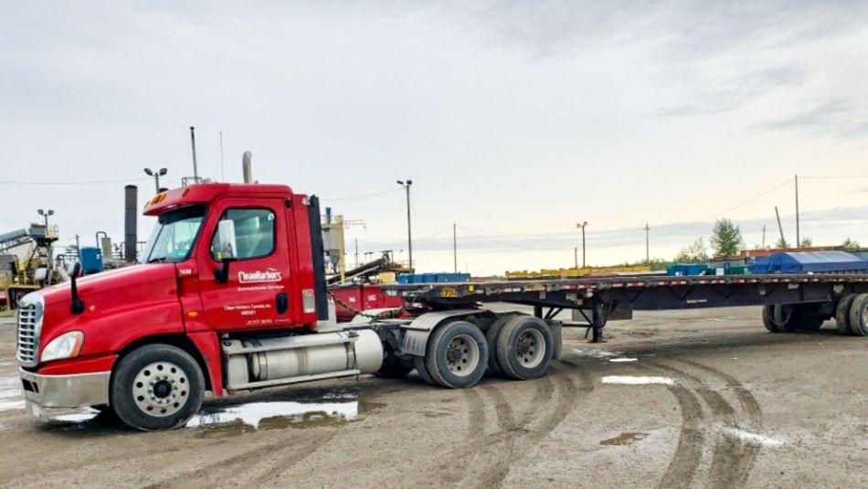 Red truck with an empty flatbed parked outside