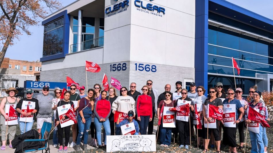 Unifor members gather outside the Clear Medical building holidng "on stike" placecards and red Unifor flags