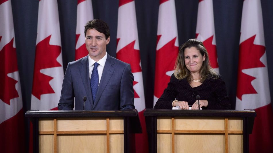 ” Justin Trudeau et Chrystia Freeland sur des podiums devant des drapeaux canadiens.