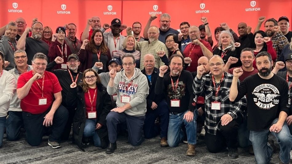 A large group photo in front of a large Unifor banner