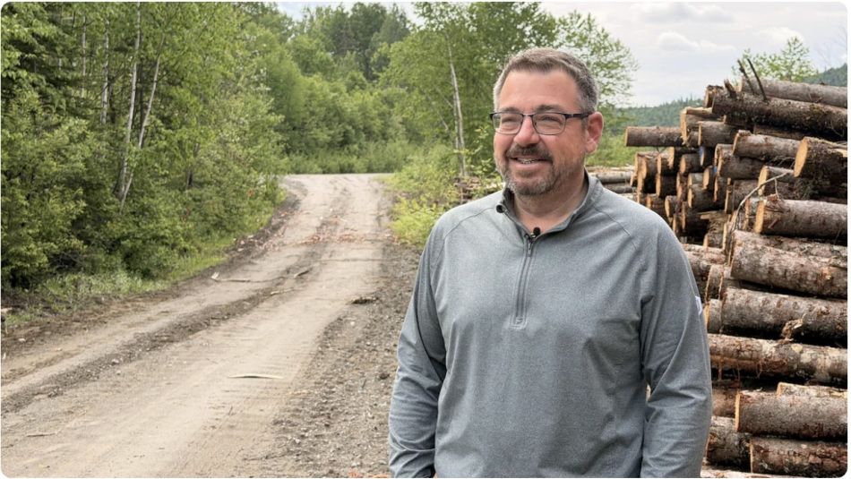 A man standing along side a forested road.
