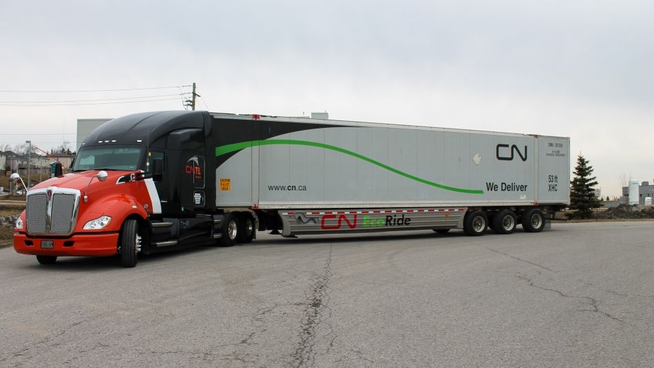 A red and black CNTL semi-truck with a long white trailer parked in an open area.