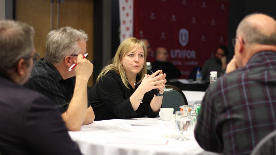 A women seated at a table talking with people in Edmusdston at the BWP meeting.