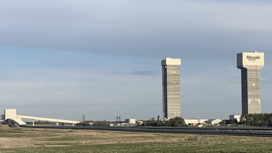 Mosaic potash facility in Esterhazy, SK. Two towers and other facility buildings from a great distance across an empty field.