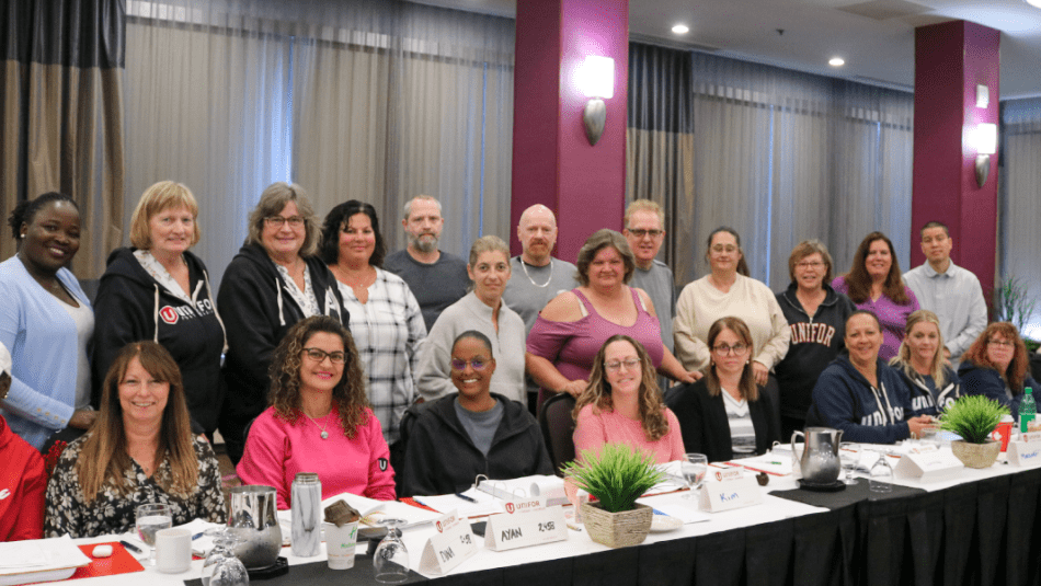 twentythree people sitting and standing in rows behind a table