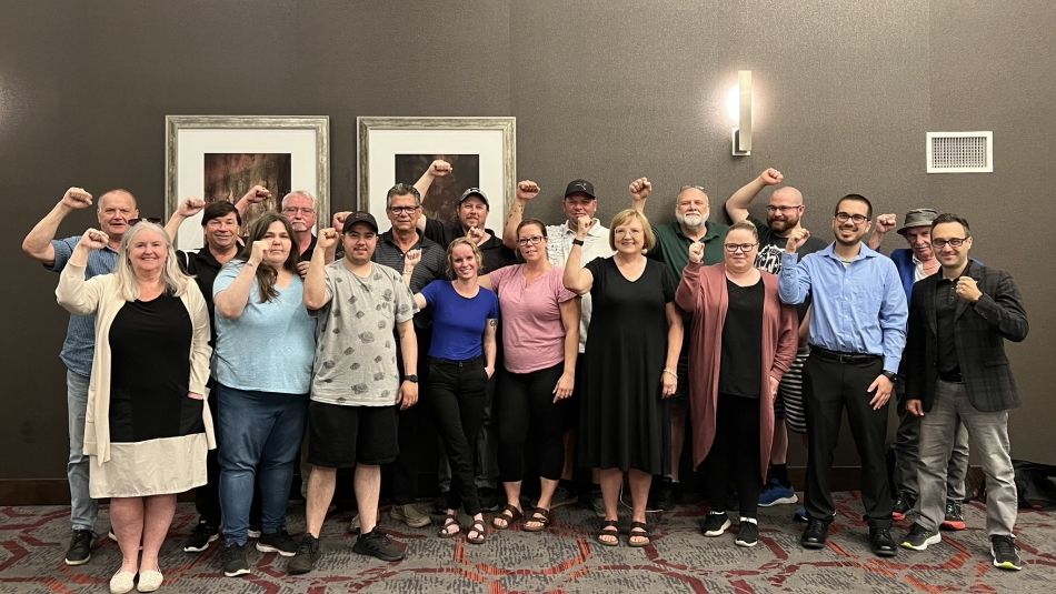 Unifor Local 414 bargaining committee members stand with Lana Payne with fists raised.