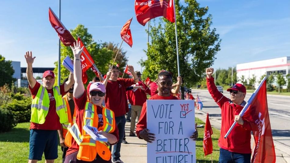 People on a picket line holding up Unifor flags and placcards