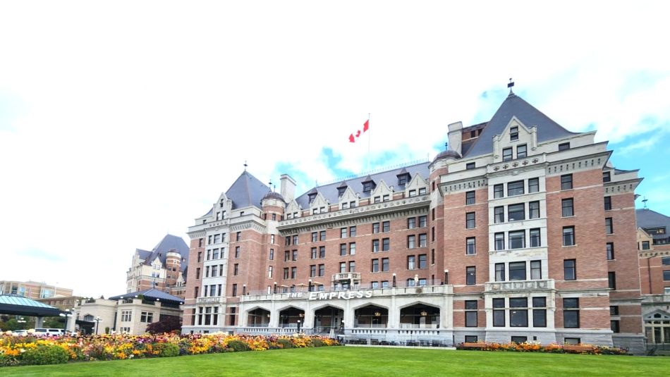 Exterior view of the Fairmont Empress Hotel with gardens and a lawn in the foreground.