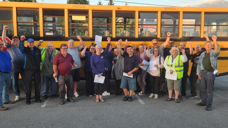 A group of people posing for a photo in front of a school bus