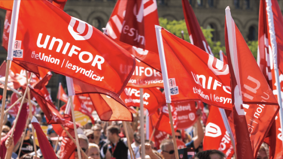 Les drapeaux d'Unifor flottent dans la foule.