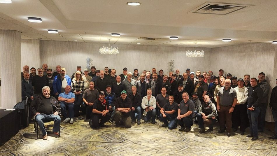 A large crowd pose for a group photo in a conference room.