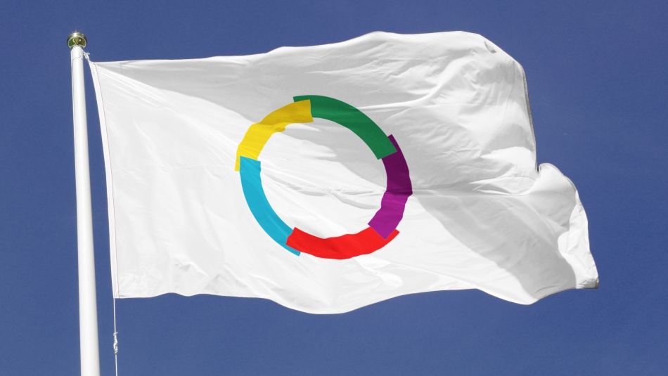 Flag of La Franchophonie Flag of La Francophonie (multicoloured empty circle on a white background) waving against a deep blue sky.
