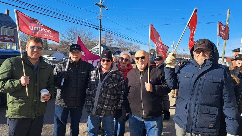 A group of Unifor members holding flags at a rally.