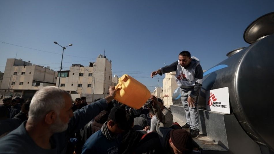 Un homme distribue un bidon d'eau à la foule.