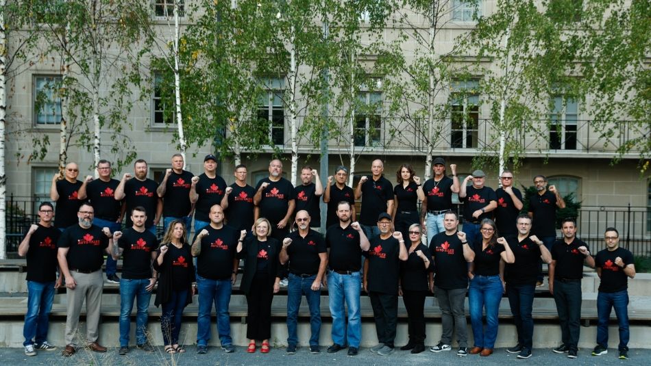 A large group of people wearing matching tshirts stand outside